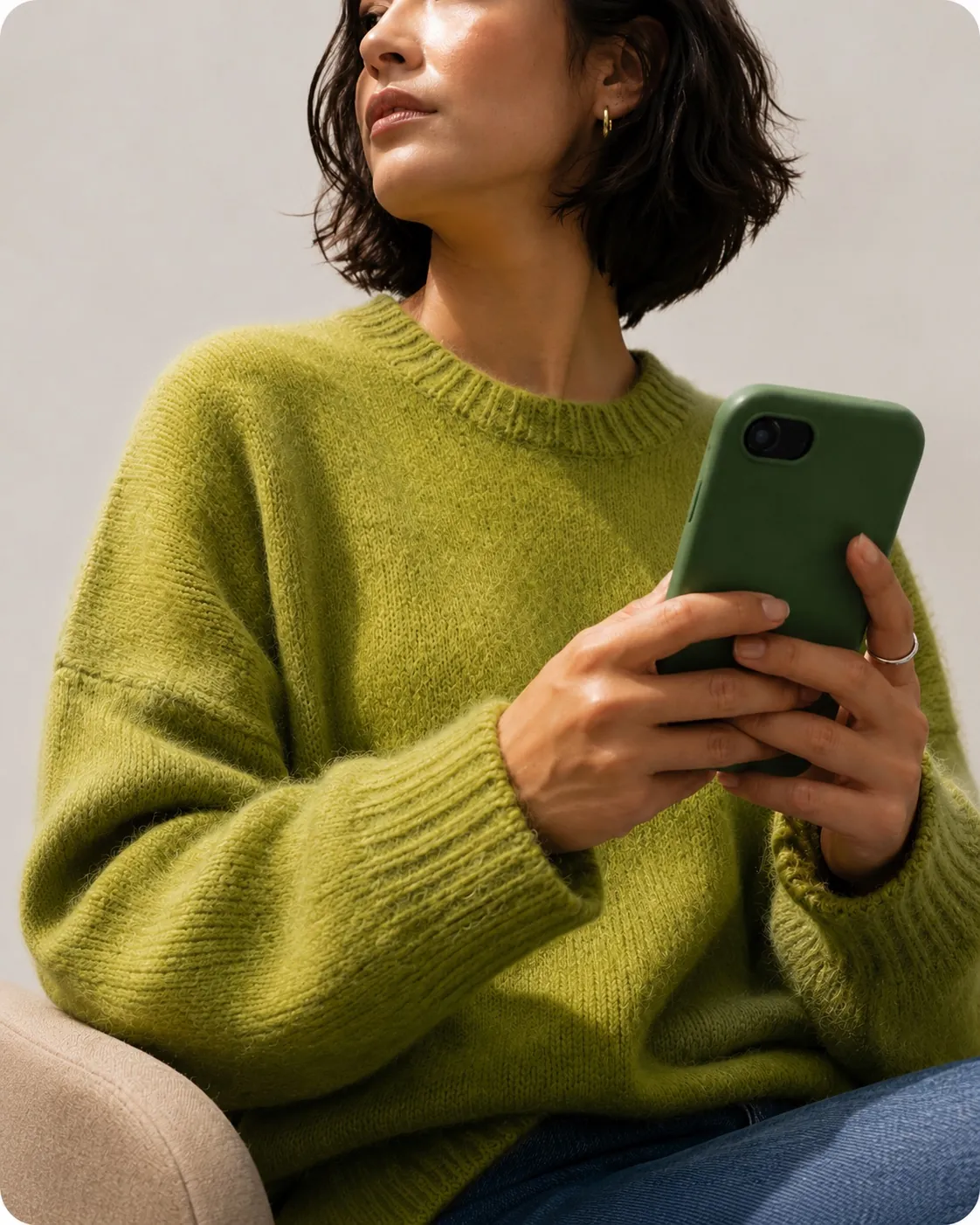 Woman in a green sweater holding a phone